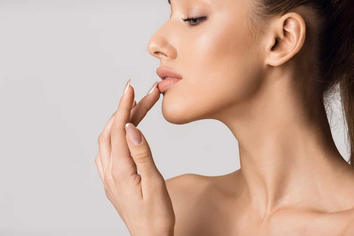 Woman touching her lips to highlight natural lip enhancement and facial balance